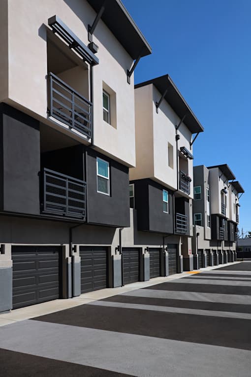 A row of modern townhouses with balconies and garages.