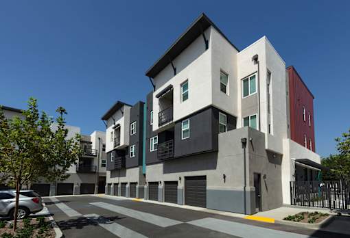 A modern multi-story building with a parking lot in front.