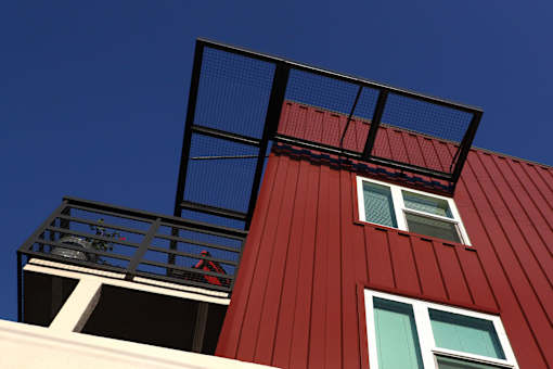 A red building with a balcony and a black railing.