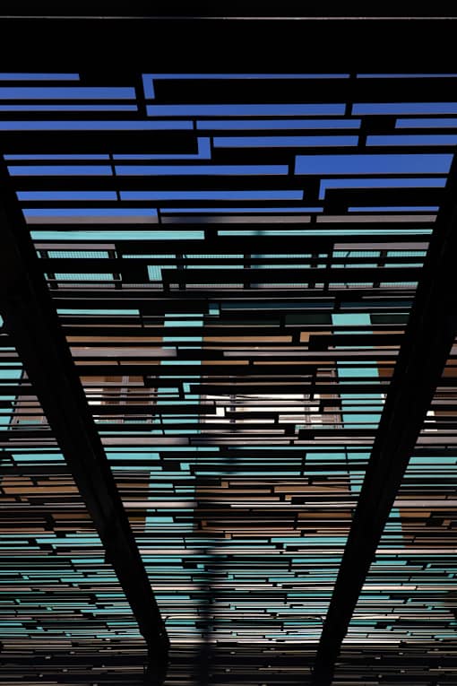 A person is standing in front of a wall with blue and brown horizontal stripes.