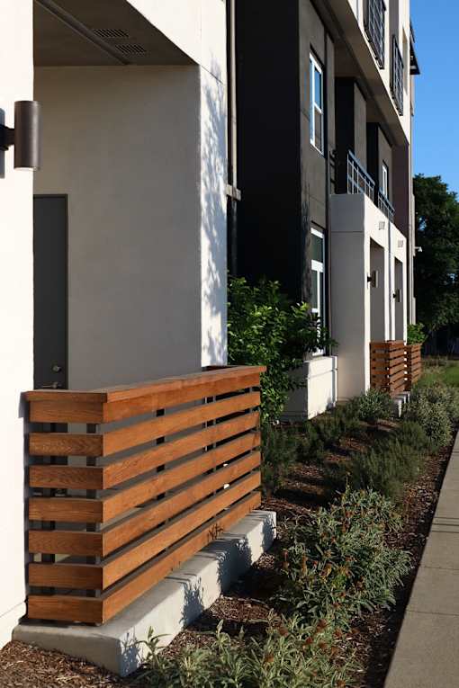 A wooden fence is in front of a white building.
