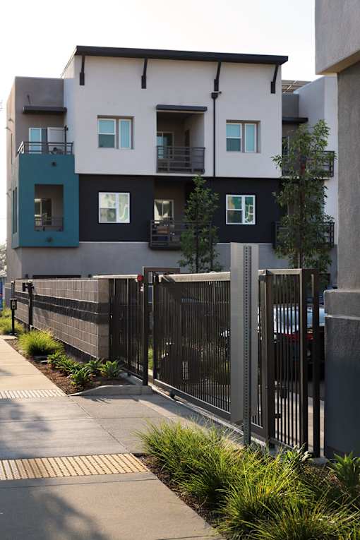 A black fence runs along a sidewalk in front of a building.