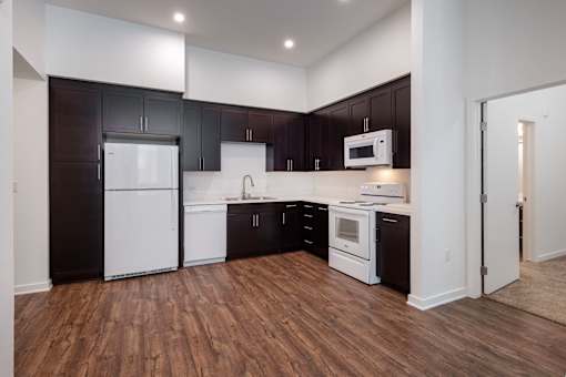 A kitchen with black cabinets and white appliances.
