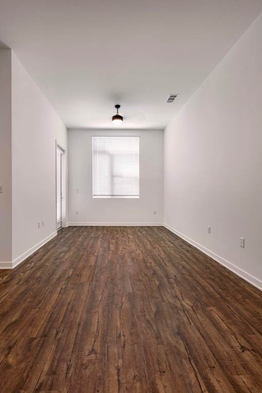 A room with wooden floors and a window letting in light.