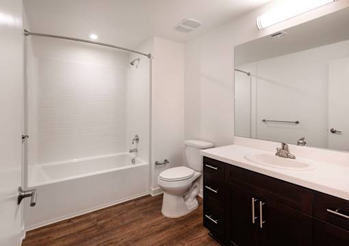 A white bathroom with a wooden floor and a white toilet.