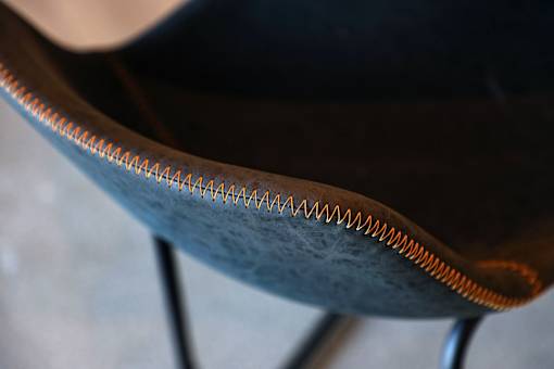 A close up of a chair with a metal frame and a leather seat.