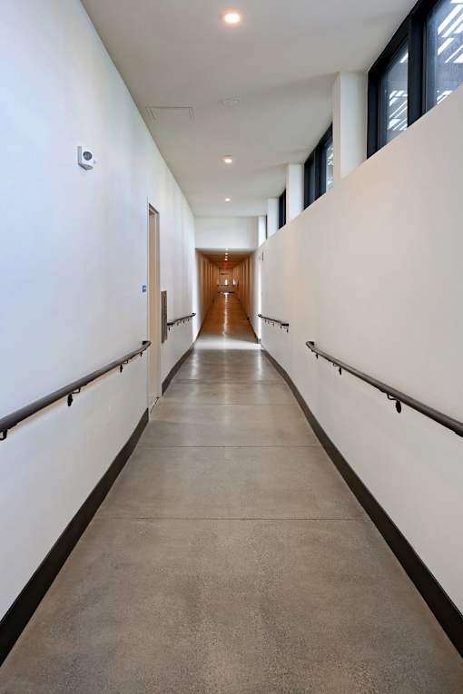 A long hallway with white walls and a brown floor.