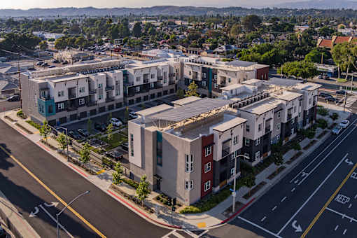 A large apartment complex is situated on a street corner with a view of the mountains in the background.