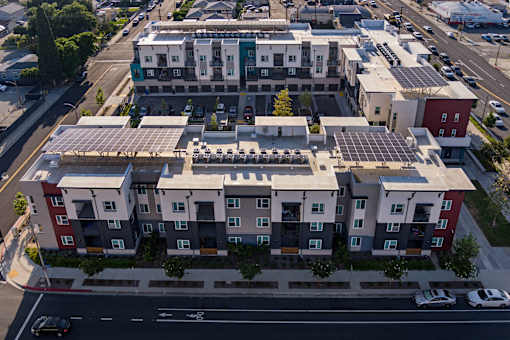 A modern apartment complex with solar panels on the roof.