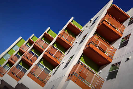 A tall building with balconies in orange and green.
