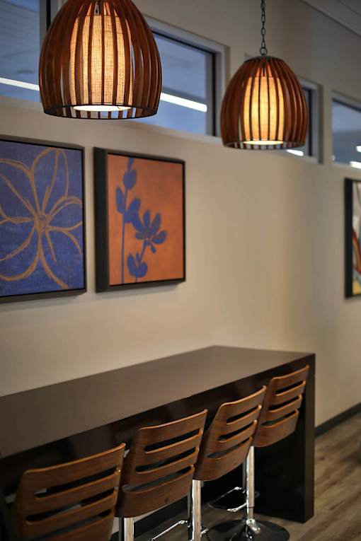 A brown wooden table with four chairs and two hanging lights.