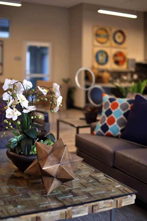 A living room with a glass table and a brown couch.