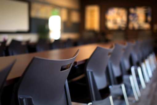 A classroom with rows of chairs and a projector screen.