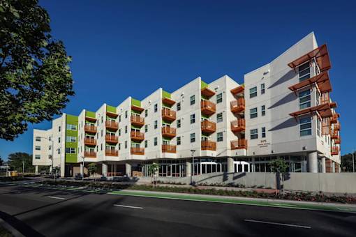 A modern building with a green and white exterior and a red balcony railing.