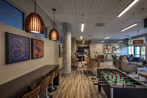 A room with a foosball table and a bar area.
