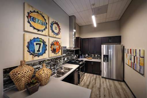 A kitchen with a refrigerator, sink, and decorative wall art.