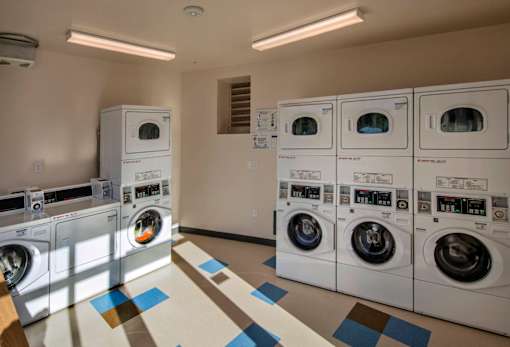 A row of white front load washing machines in a laundromat.