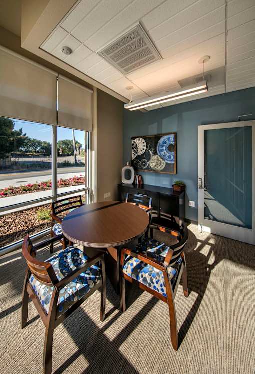 A conference room with a table and chairs and a window overlooking a garden.