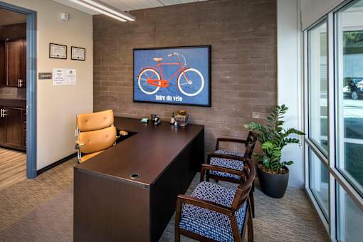 A room with a brown desk and a bicycle picture on the wall.