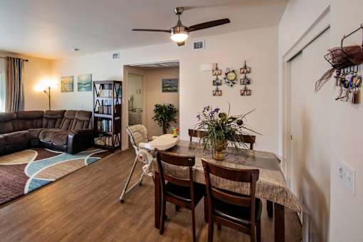 A dining room with a table set for two and a couch.