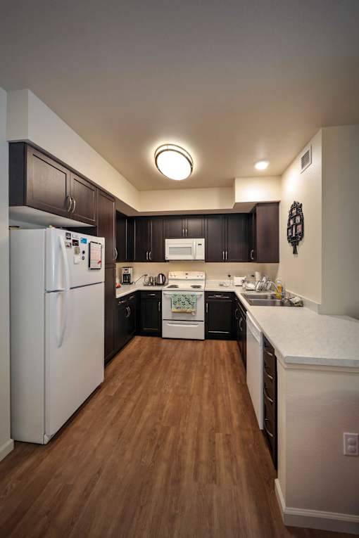 A kitchen with a white refrigerator and wooden floors.