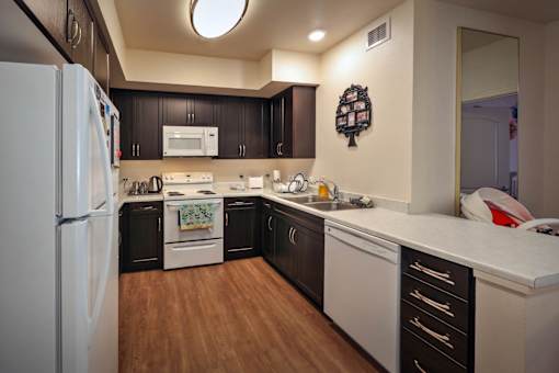 A kitchen with a white refrigerator and black cabinets.