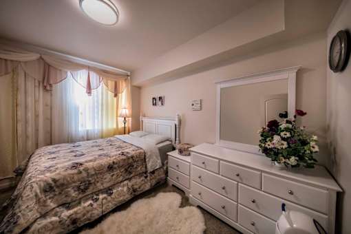A bedroom with a bed and a dresser with a mirror above it.