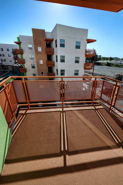 A balcony with a brown floor and a railing overlooking a river.