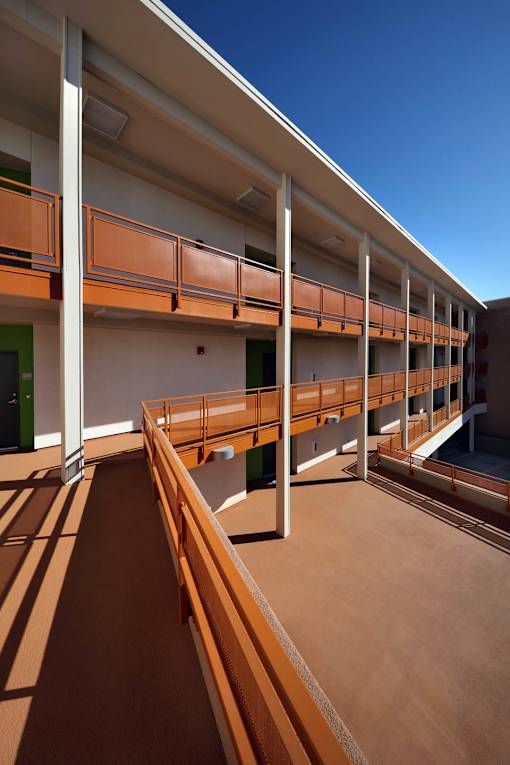 A long corridor with orange railings and white pillars.