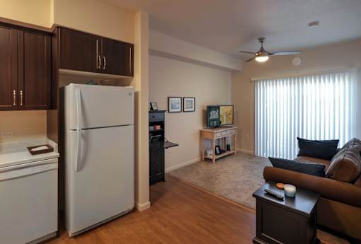 A kitchen with a refrigerator, a stove, and a dining table with chairs.