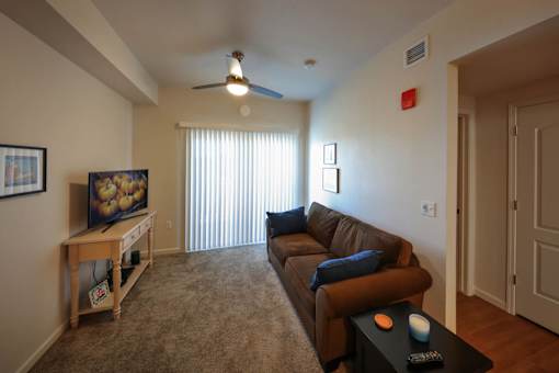 A living room with a brown couch and a ceiling fan.