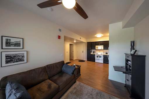 A living room with a brown couch and a ceiling fan.