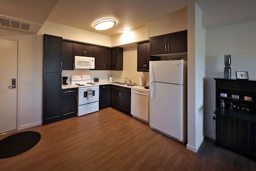 A kitchen with black cabinets and a white fridge.