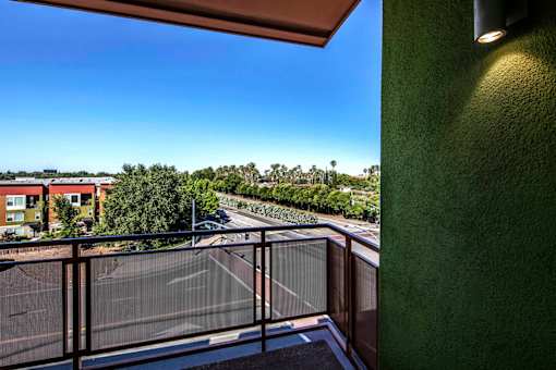 A balcony with a view of a road and trees.
