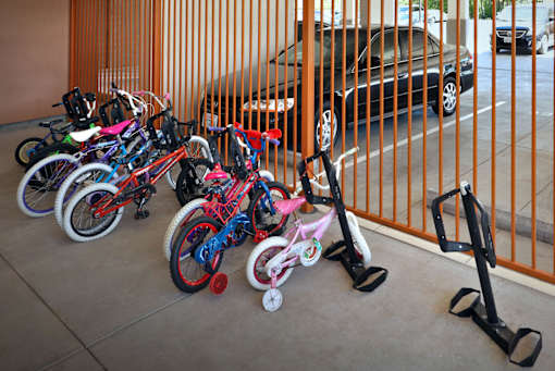 A row of bikes and scooters are lined up against a fence.