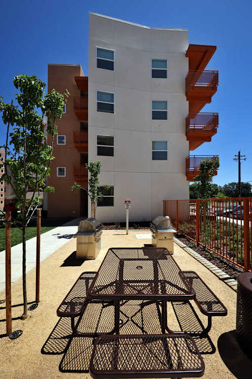 A modern building with orange balconies and a black metal table in front.