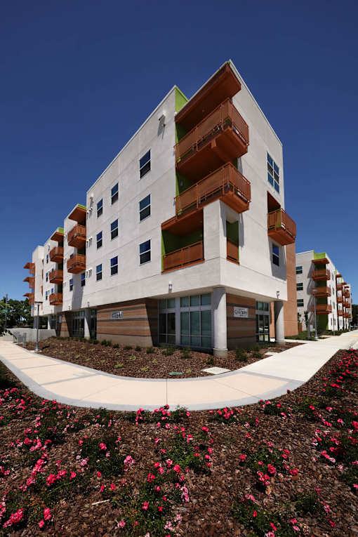 A modern building with a white facade and balconies on the upper floors.