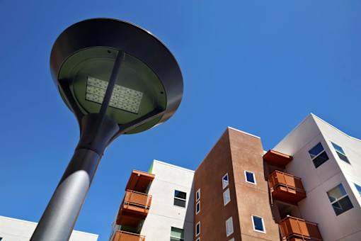 A street lamp stands in front of a building with orange balconies.