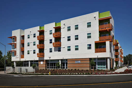 A modern apartment building with white walls and orange balconies.