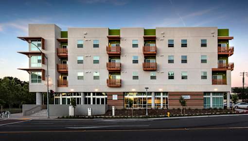 A modern apartment building with balconies on the second floor.