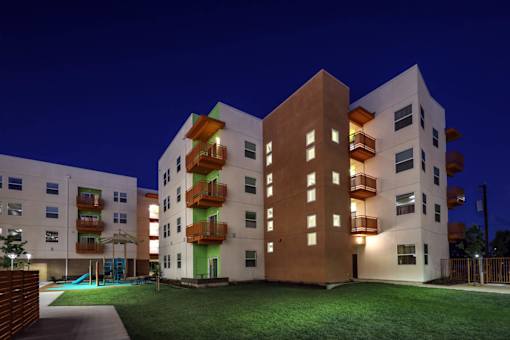 A modern apartment complex with balconies and lights on.