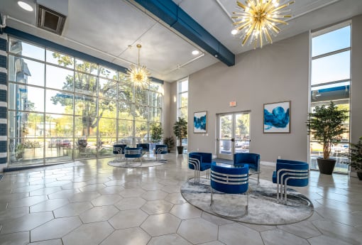 a lobby with blue chairs and large windows and a chandelier