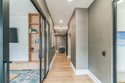 A long hallway with a rug on the floor and a door on the right.