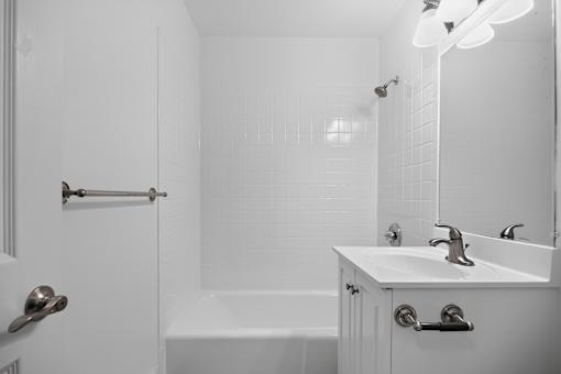 A white bathroom with a tub, sink, and mirror.