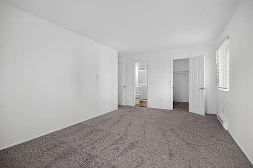 A carpeted room with a doorway leading to another room.