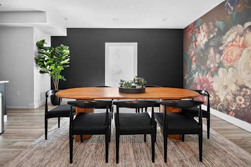 A dining room with a round wooden table and six chairs.