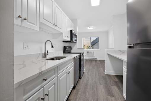 A kitchen with white cabinets and a black dishwasher.