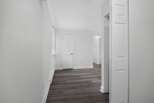 A hallway with a white door and a wooden floor.