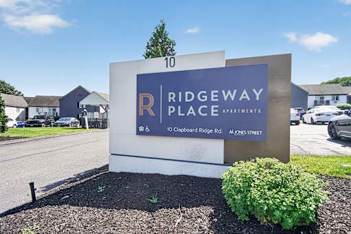 A sign for Ridgeway Place Apartments stands in front of a row of houses.