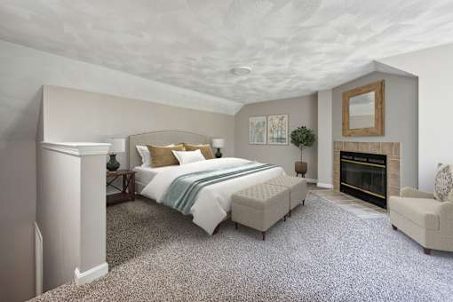 A bedroom with a large bed, carpet, a fireplace, and a chair at Birchwood Hills, Shirley MA.